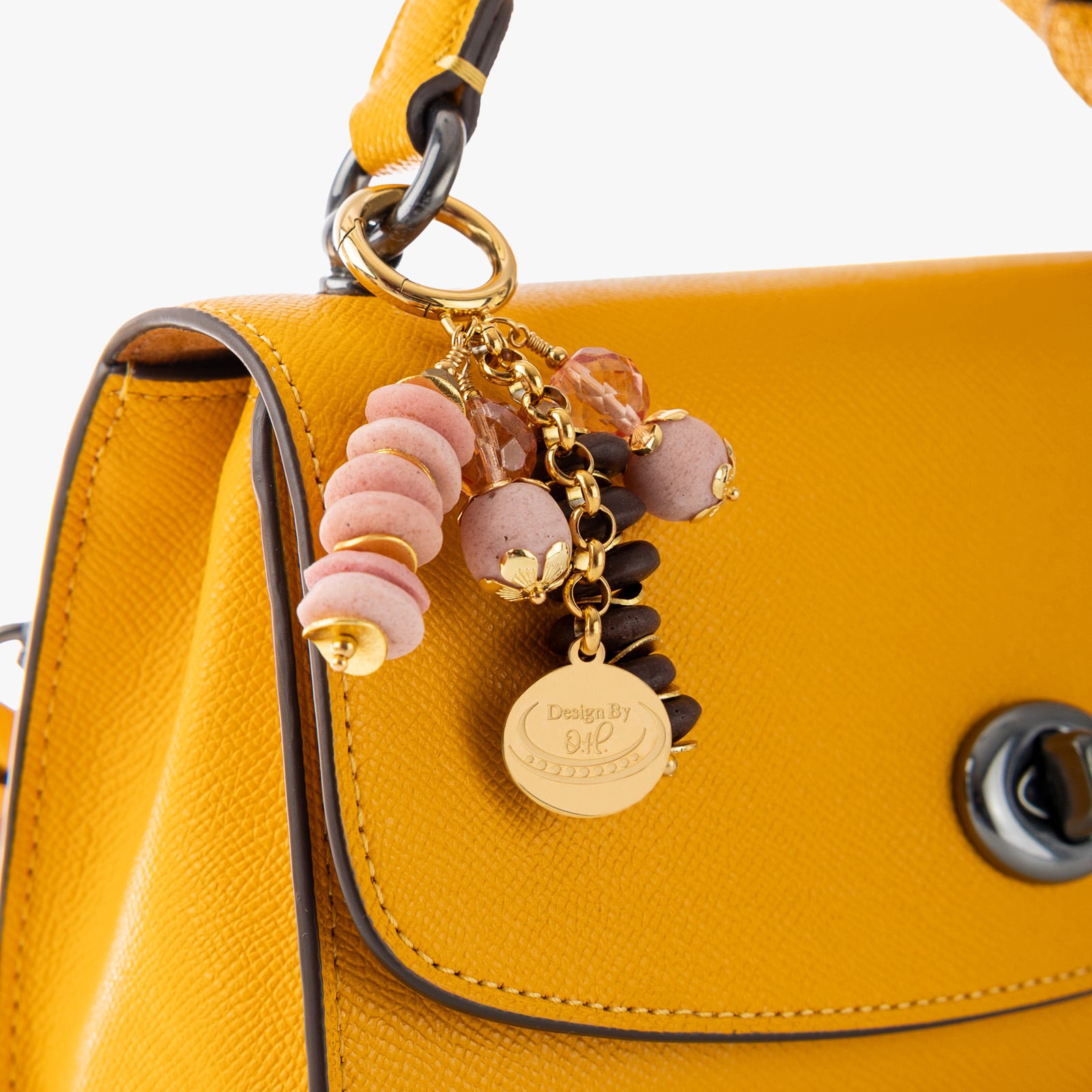 Close-up of Esi charm showing pink and brown sandcast beads paired with gold wavy disc accents symbolizing assertiveness.