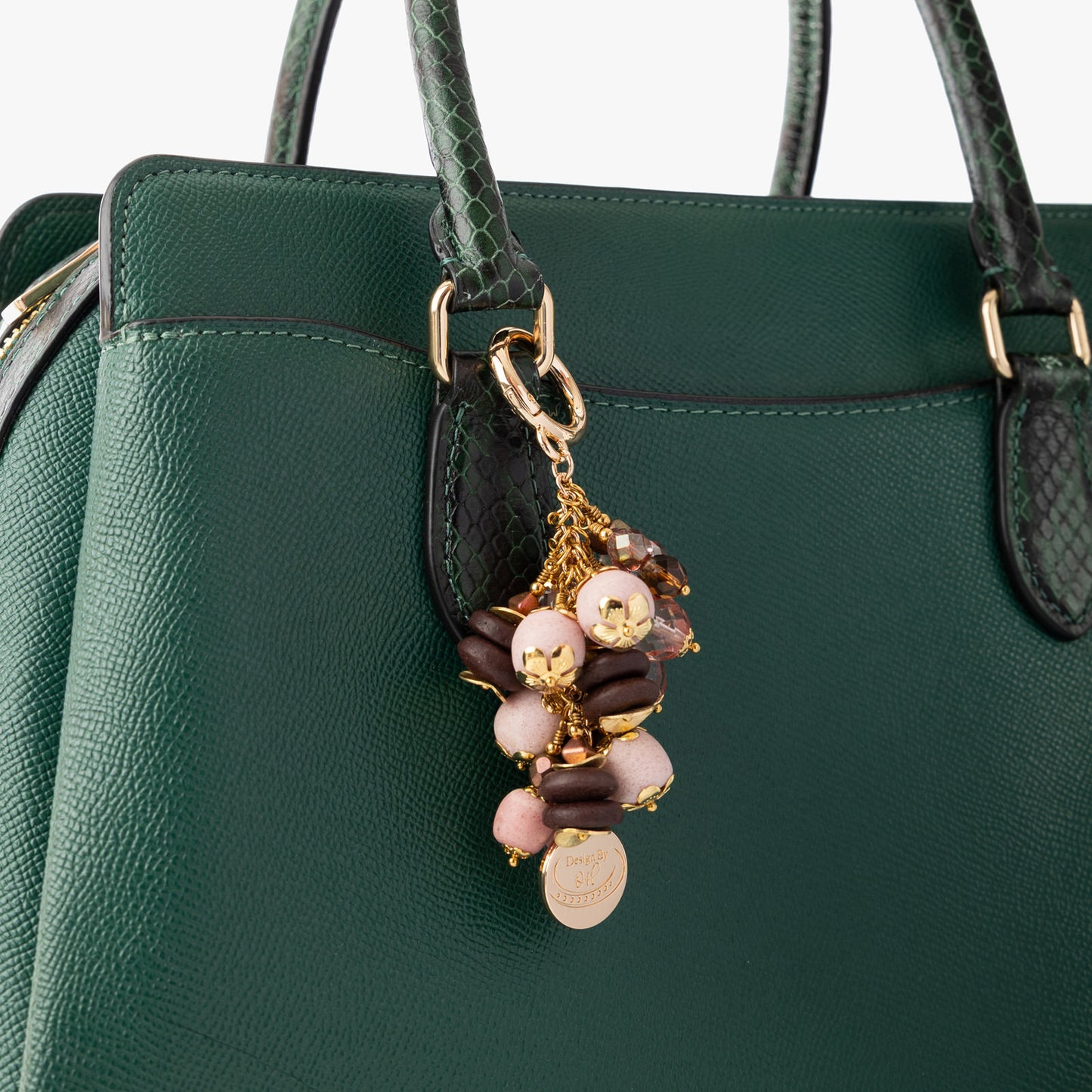 Esi Bag Charm clipped to a handbag, representing assertiveness with its pink and brown bead palette.
