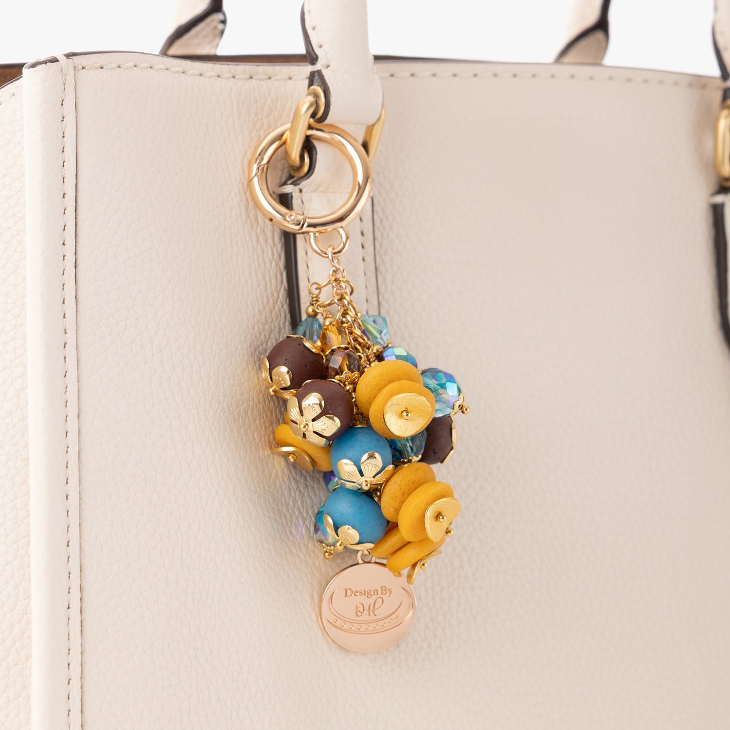 Close-up of Odamea charm showing textured brown and aqua beads paired with Czech crystals and gold wavy discs.