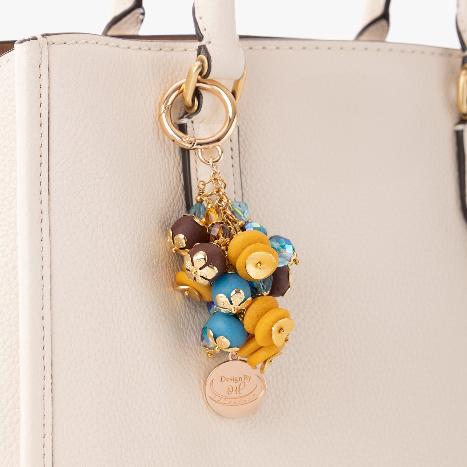 Close-up of Odamea charm showing textured brown and aqua beads paired with Czech crystals and gold wavy discs.