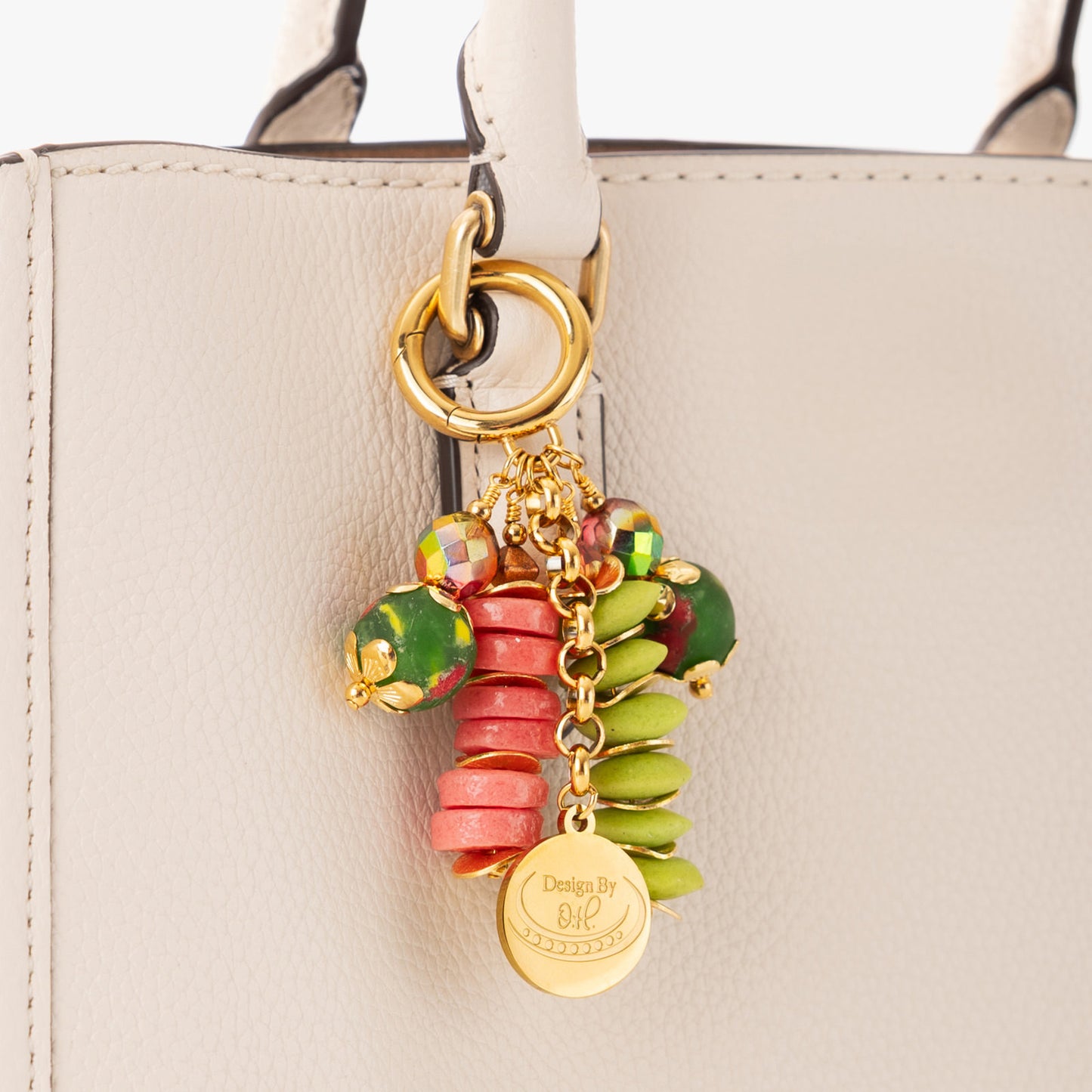 Close-up of Sonkyi charm showing bright pink and lime green recycled glass beads with gold wavy discs.