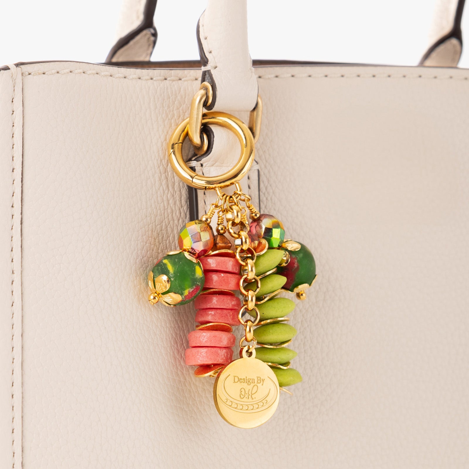 Close-up of Sonkyi charm showing bright pink and lime green recycled glass beads with gold wavy discs.