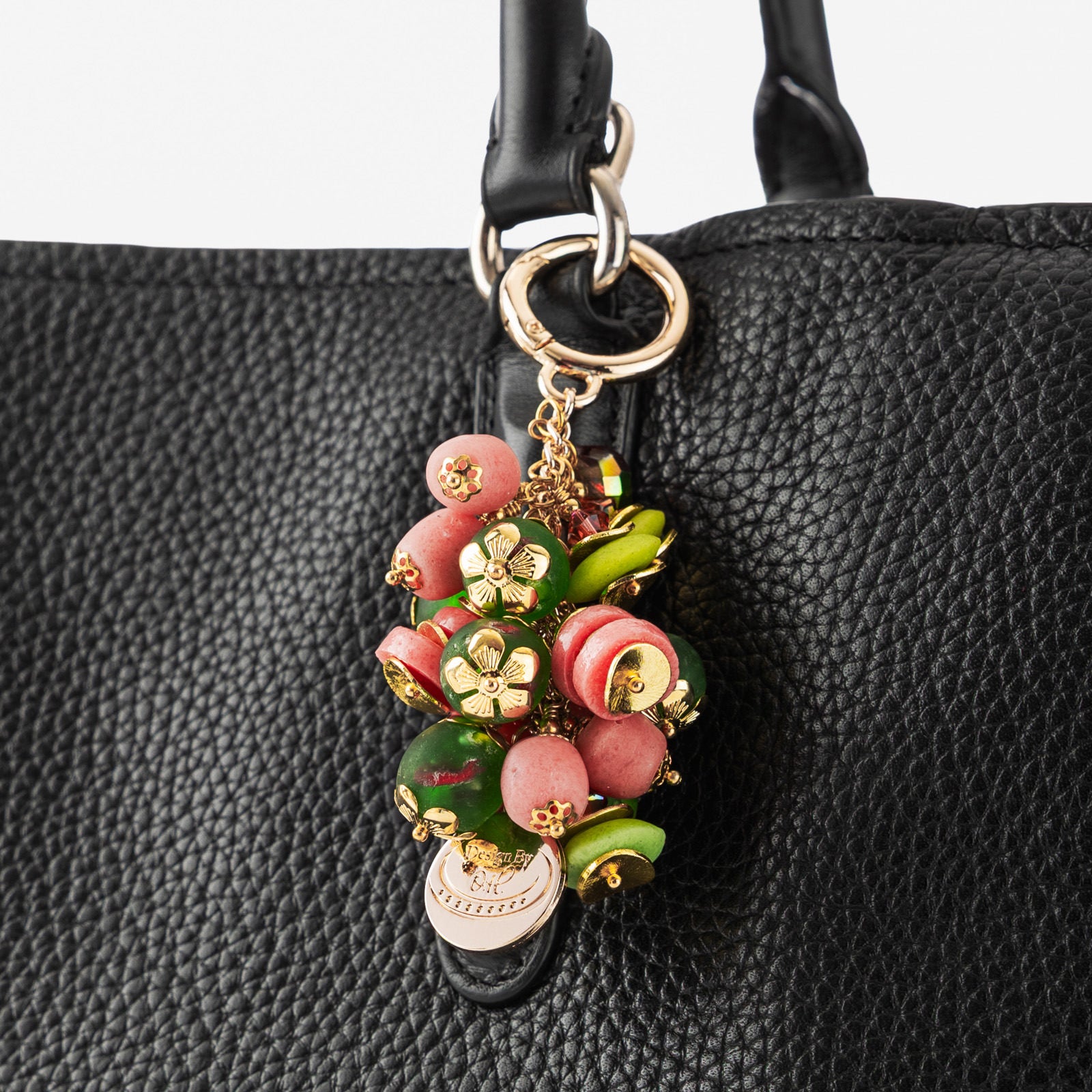 Sonkyi Bag Charm attached to a handbag, featuring its vibrant pink and lime green palette symbolizing confidence and boldness.